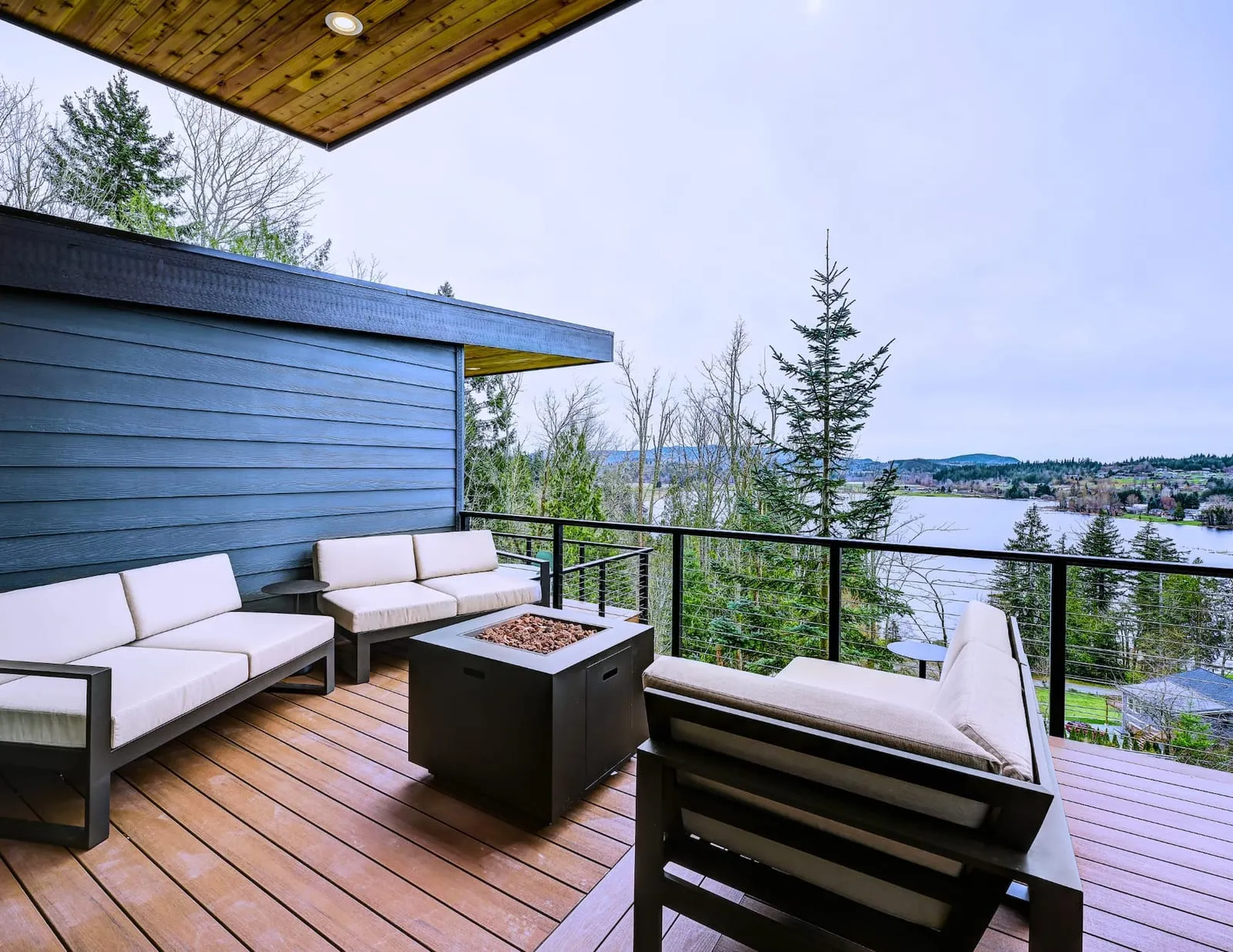A covered cabin deck with a fire pit overlooking Clear Lake
